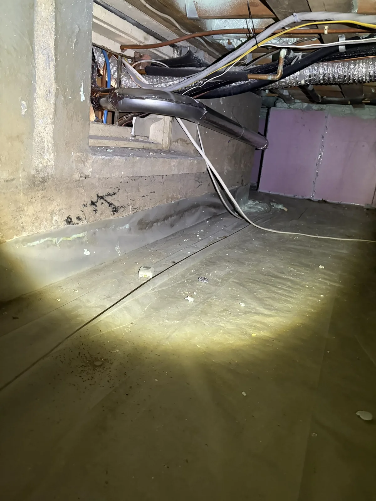 A dryer duct run inspected by flashlight in a crawlspace