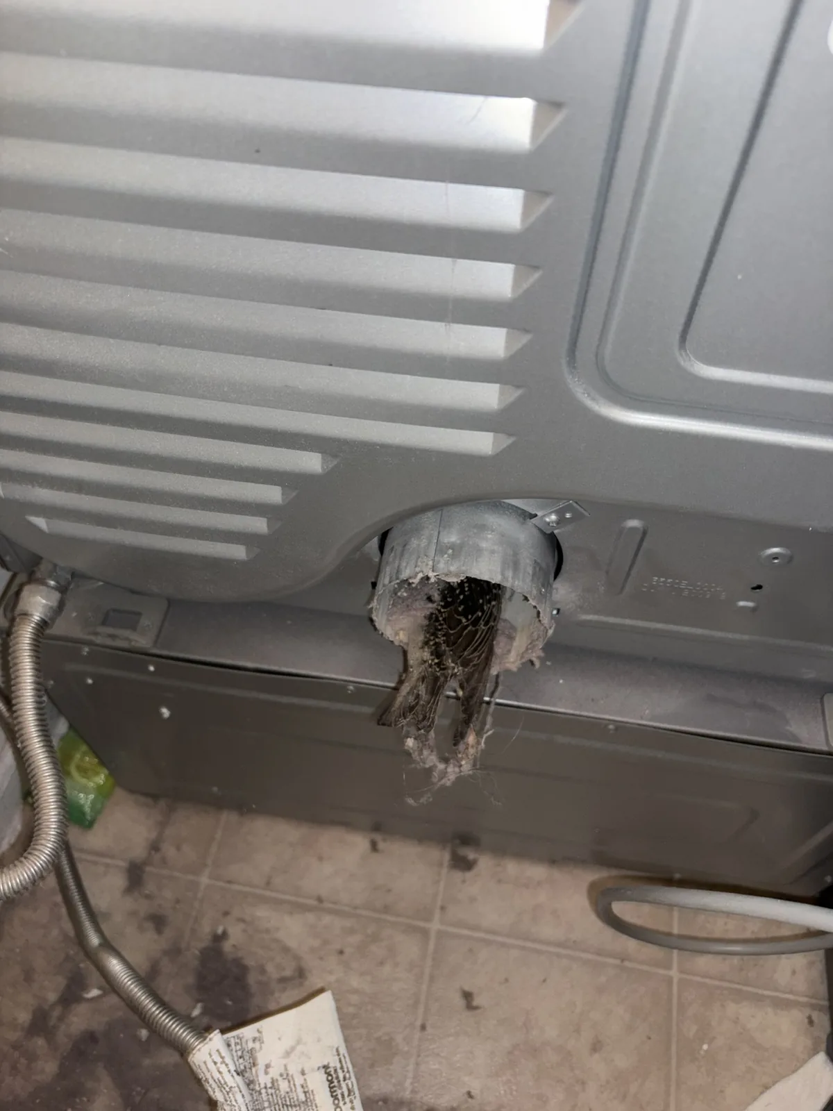The exhaust outlet on the back of a dryer before reconnecting the hose