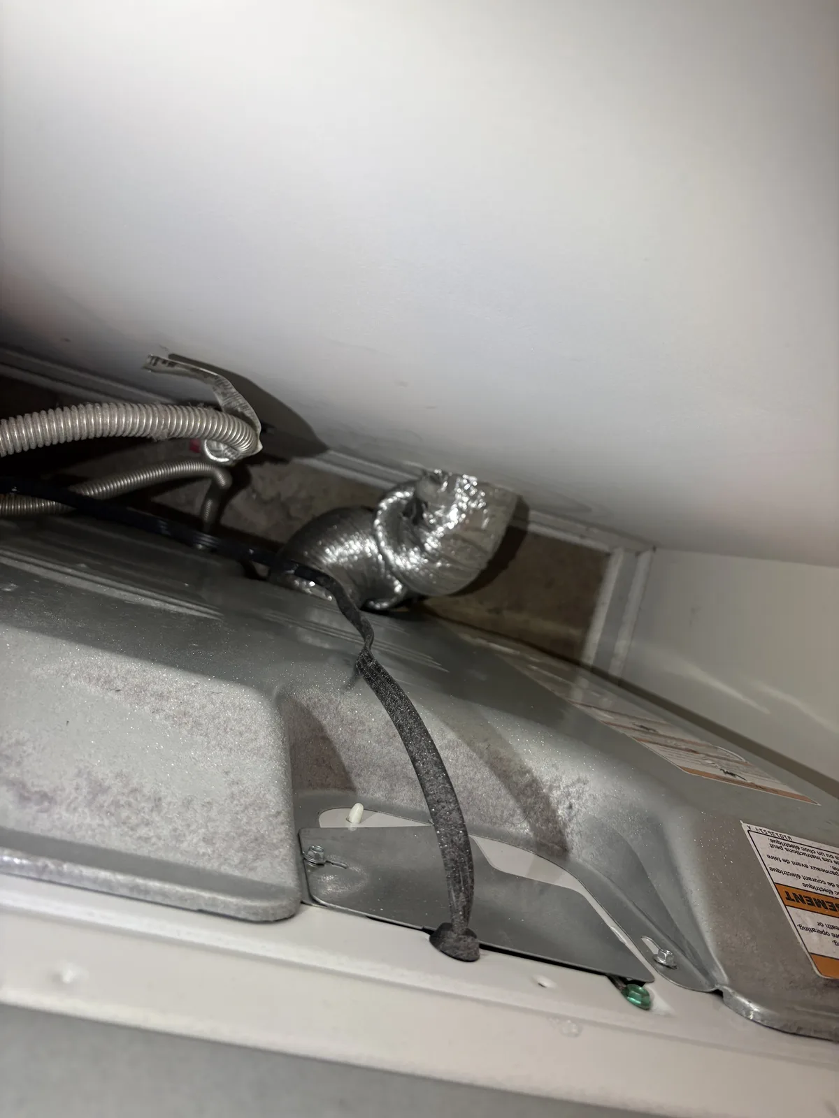 A semi-rigid DryerFlex hose clamped to the exhaust outlet behind a dryer