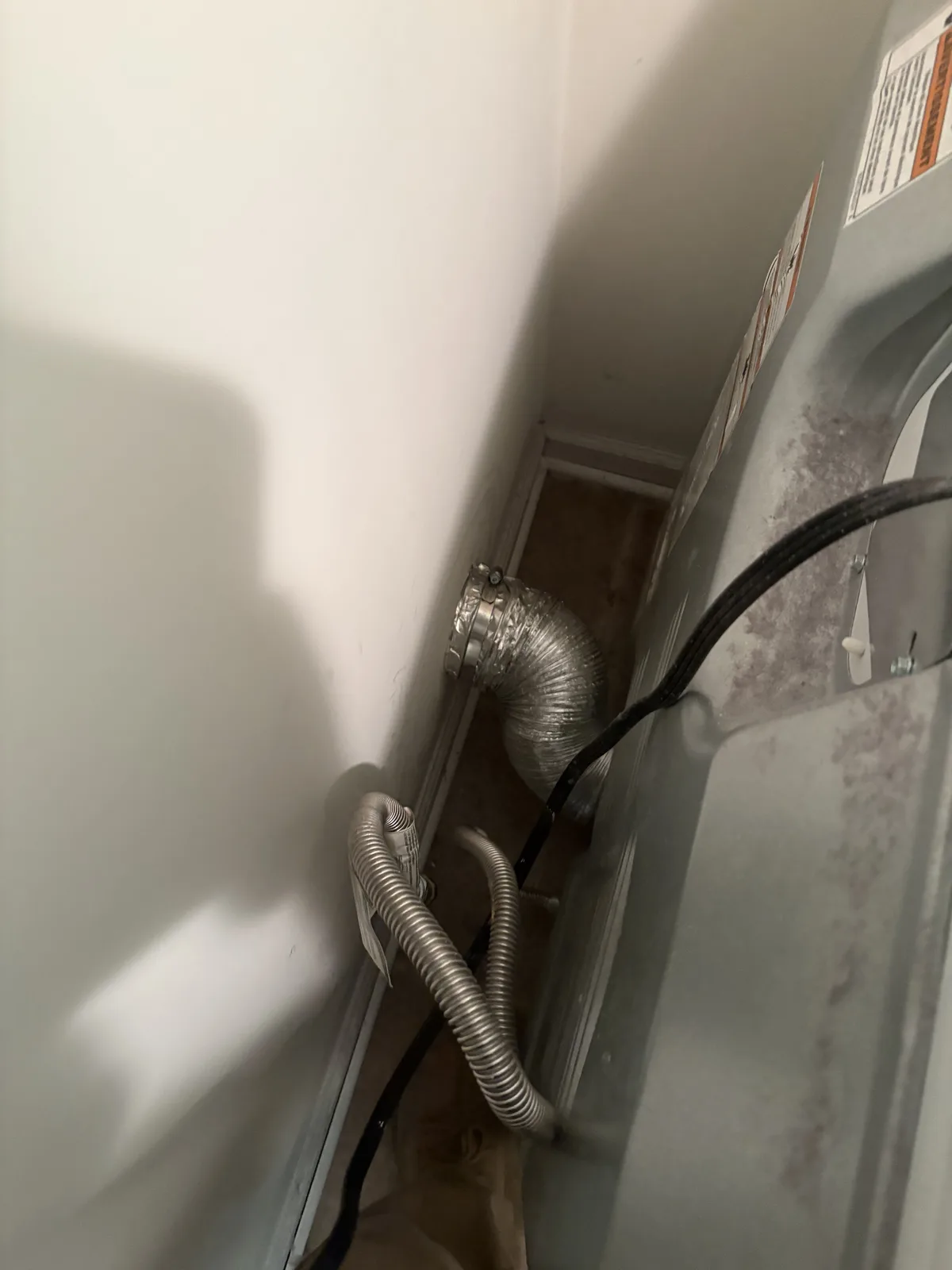 A semi-rigid DryerFlex hose running from the back of a dryer to the wall duct