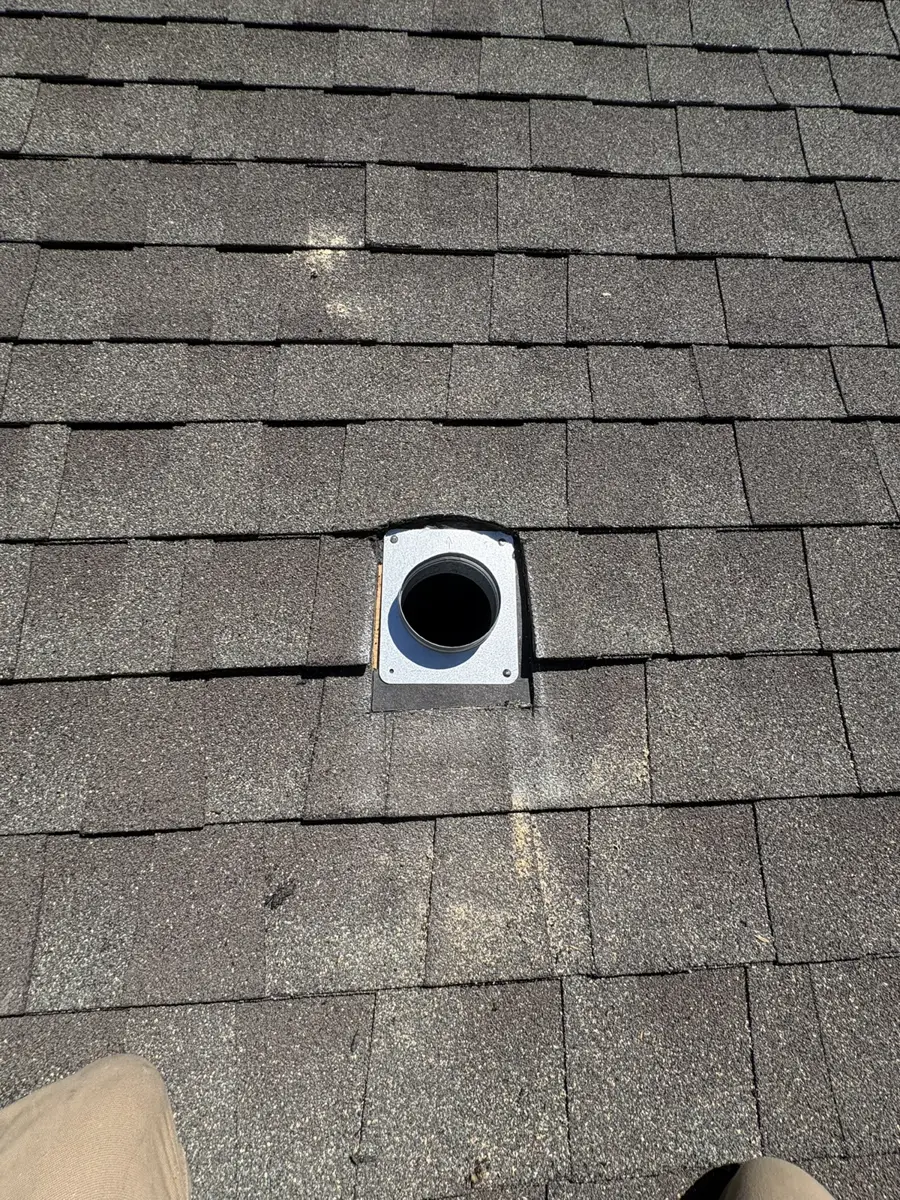 A roof dryer vent flashing with an open duct on an asphalt shingle roof